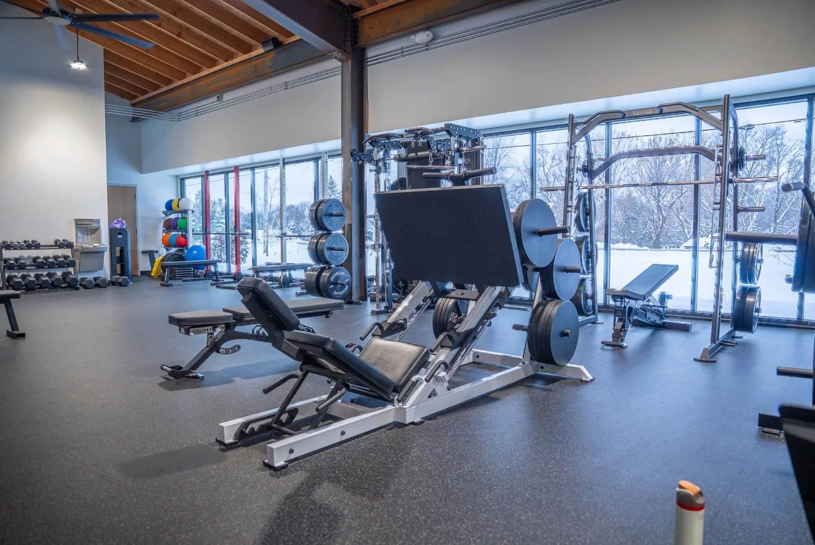 Strength machines and benches near the front windows of VirtueHall with a power rack in view