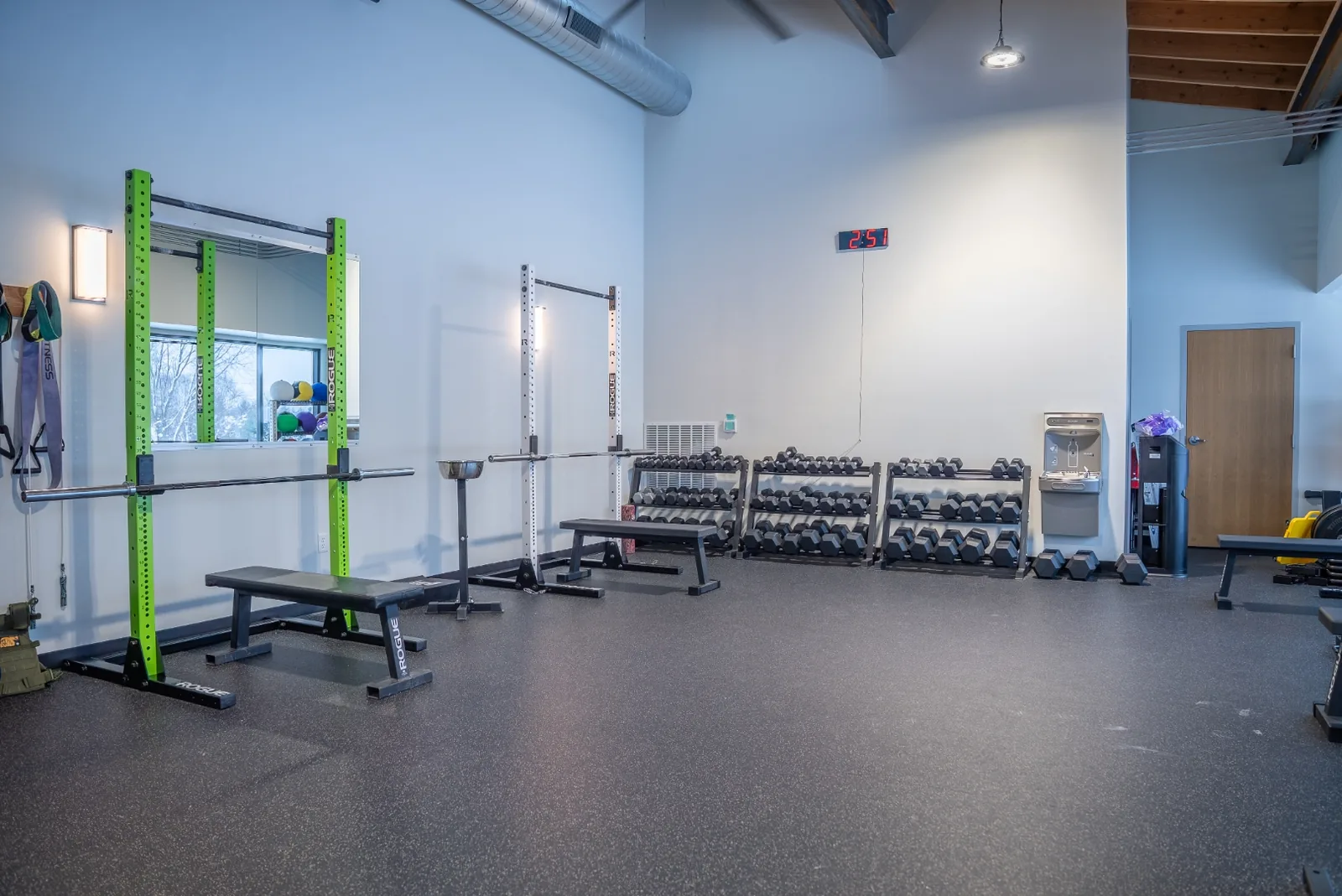 A row of treadmills and cardio equipment at VirtueHall beside the entrance and windows