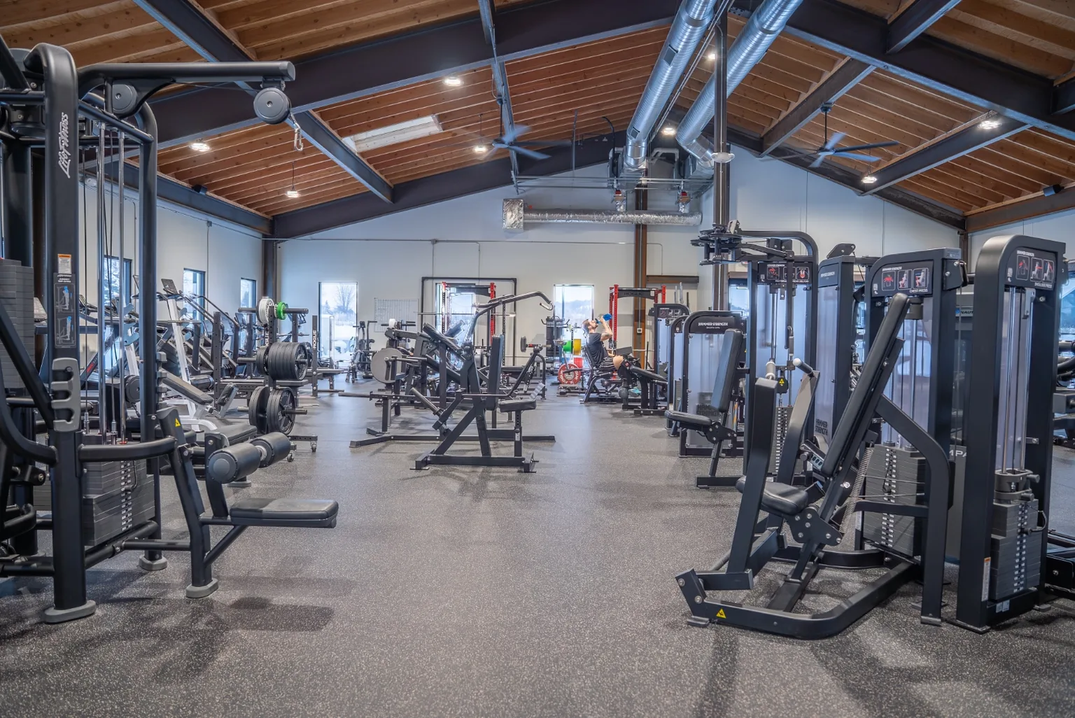 The VirtueHall machine and strength floor — selectorized machines, plate-loaded equipment, and power racks under the vaulted ceiling