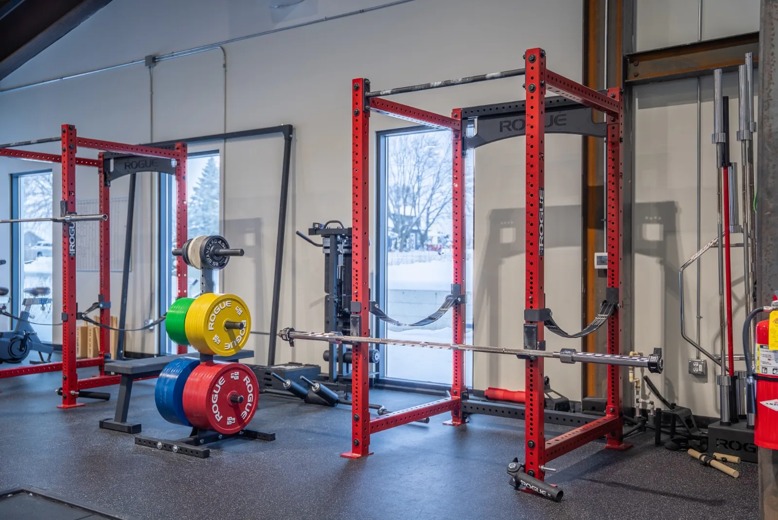 Wide view of the VirtueHall training floor — rows of strength machines and free weights under the vaulted wood ceiling